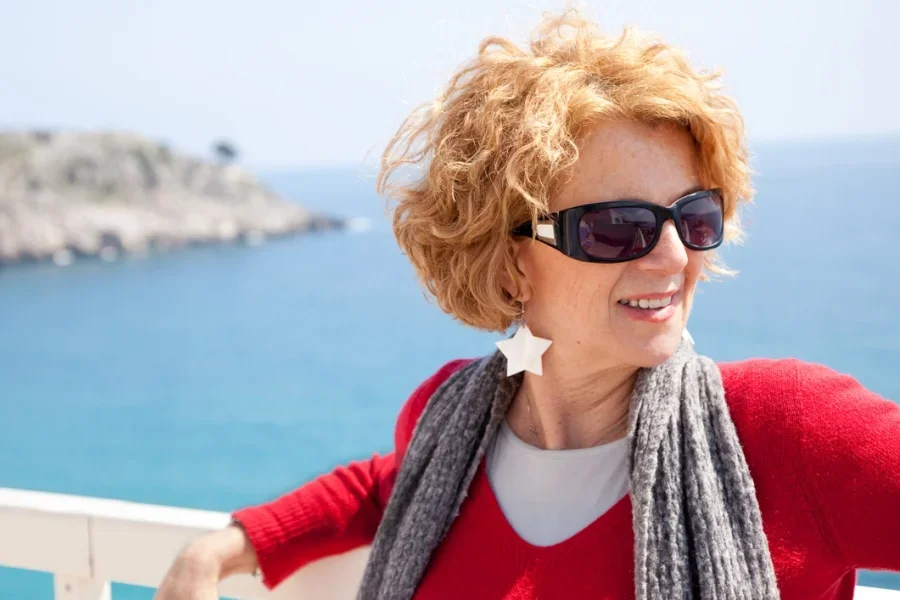 Femme avant-gardiste au bord de la mer portant des boucles d'oreilles en forme d'étoiles épaisses