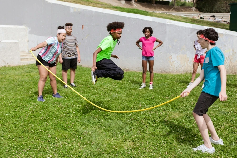 Group of children having fun jumping rope on a sunny day in the park