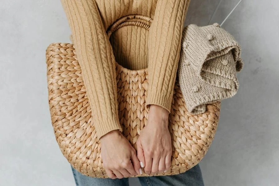 Hands of a person holding a brown basket bag