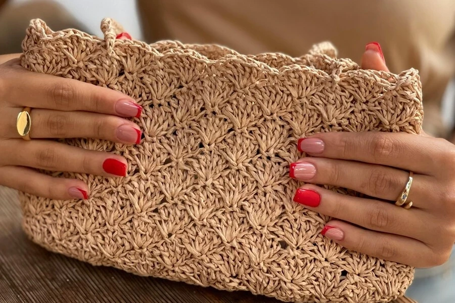 Hands of a person holding a woven handbag