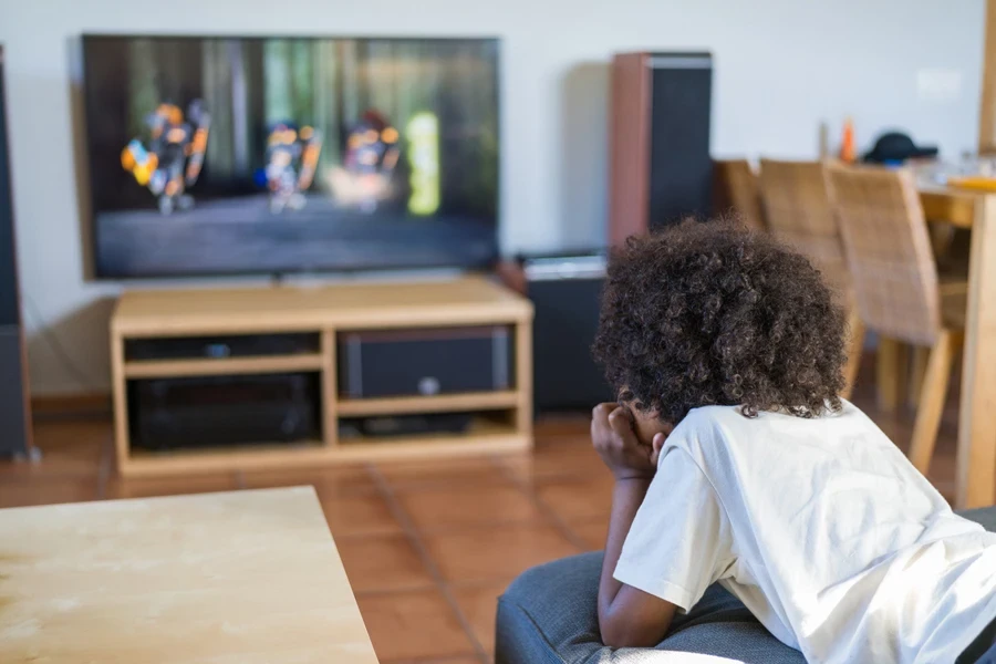 Kid watching TV with fresh new curly haircut
