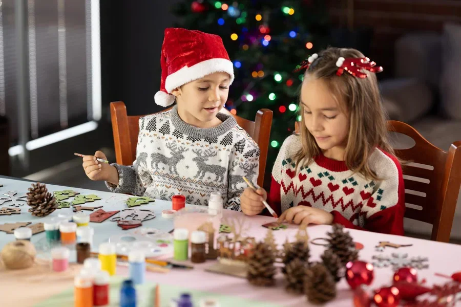 Niño y niña pintando y preparando decoraciones navideñas en casa