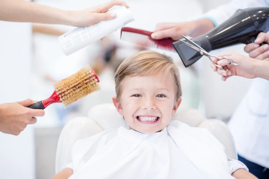 Little boy sitting in barber’s chair with straight hair