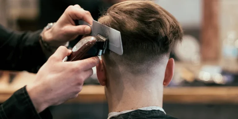 Hombre en una barbería recibiendo un corte de pelo con degradado medio