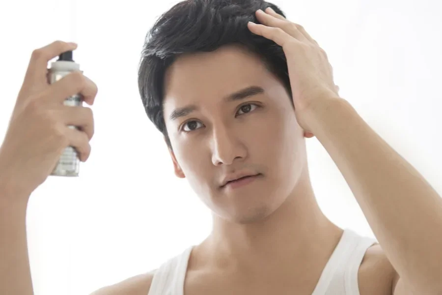Hombre peinando su cabello con spray de sal marina para darle textura