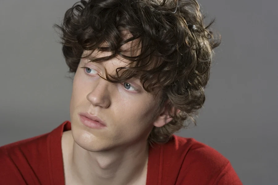 Man with mid-length curly hair and choppy bangs