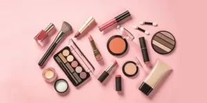 Multiple makeup tools and products on a pink background