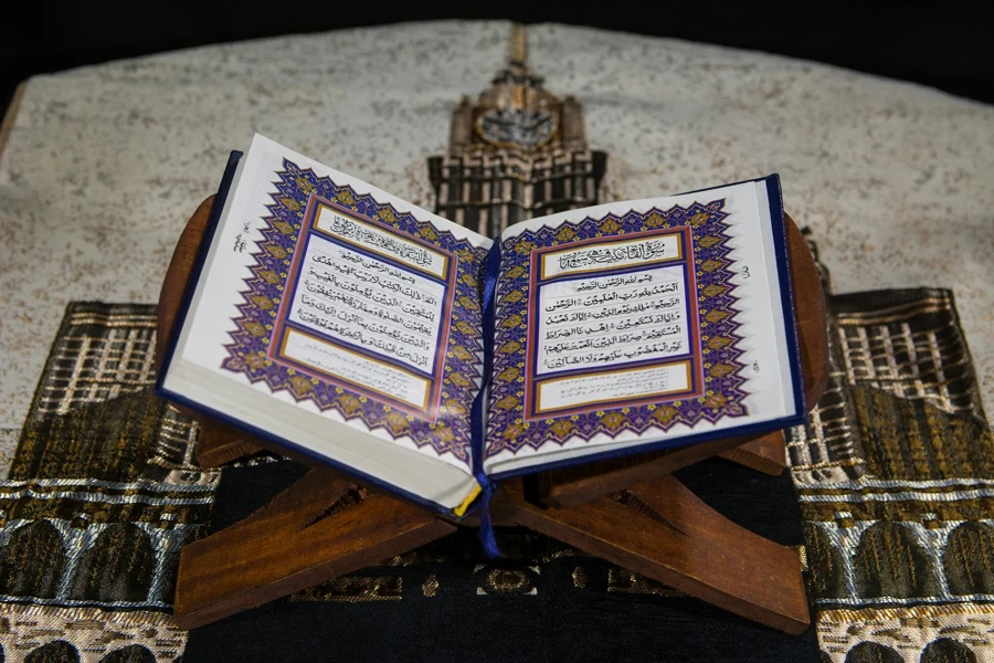 Muslims Islamic Holy Book Quran Majid with Quran wooden stand and Janamaz Prayer Rug in the background 2