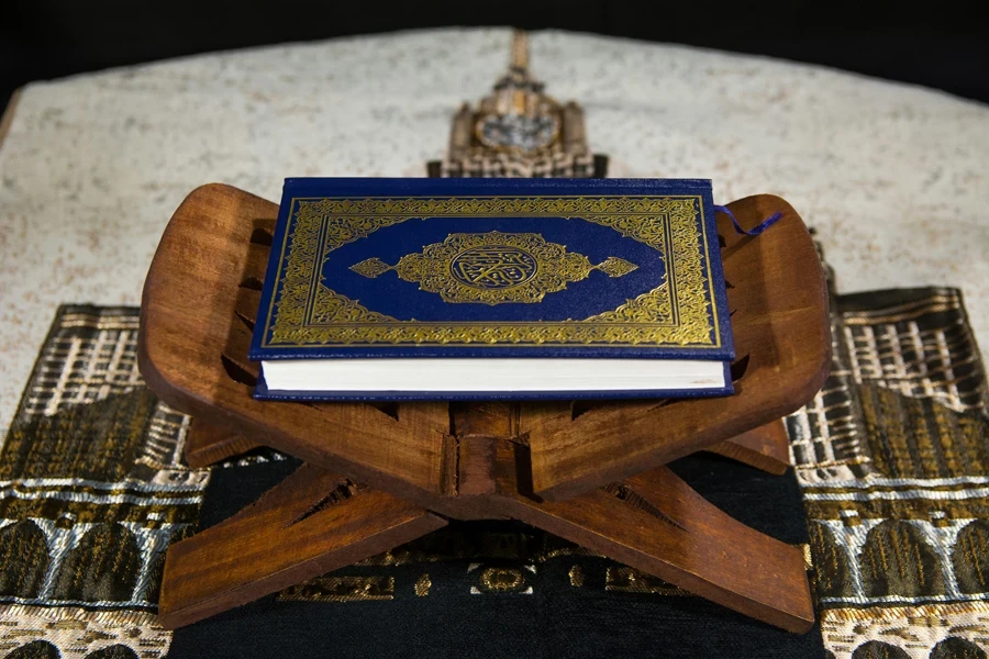 Muslims Islamic Holy Book Quran Majid with Quran wooden stand and Janamaz Prayer Rug in the background4