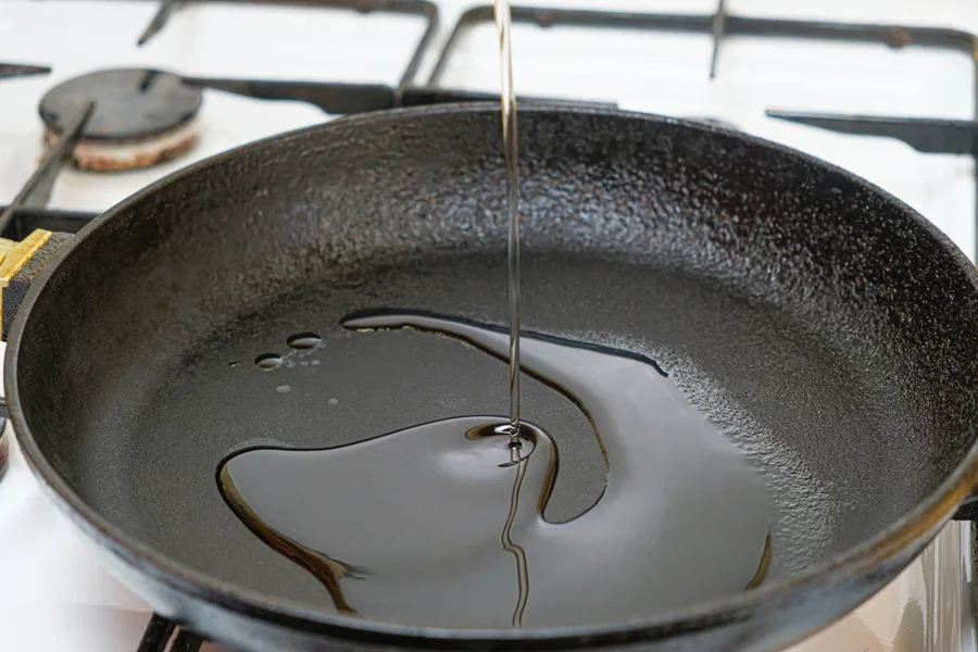 鋳鉄製のフライパンに油を注いでいる
