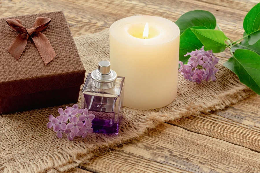 Perfume beside a scented candle and flowers
