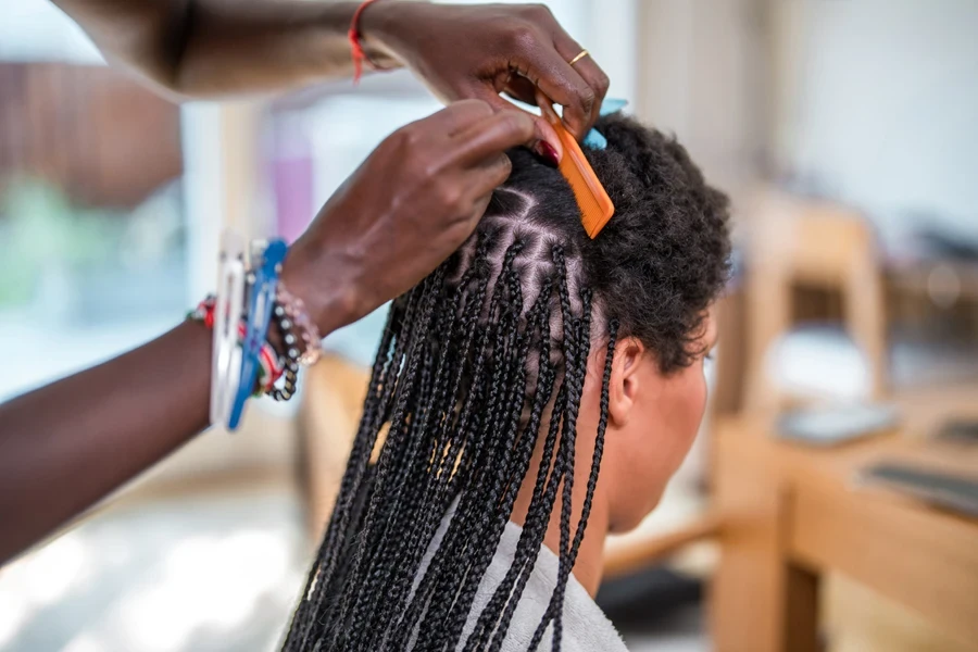 Person braiding a young woman’s hair