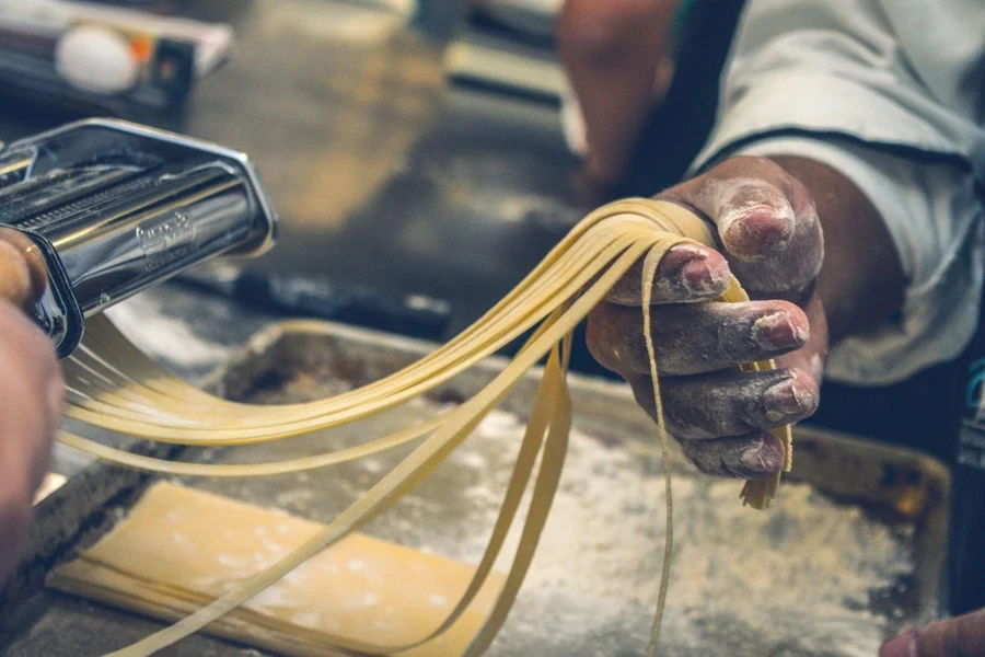 Person making dough sheet into pasta