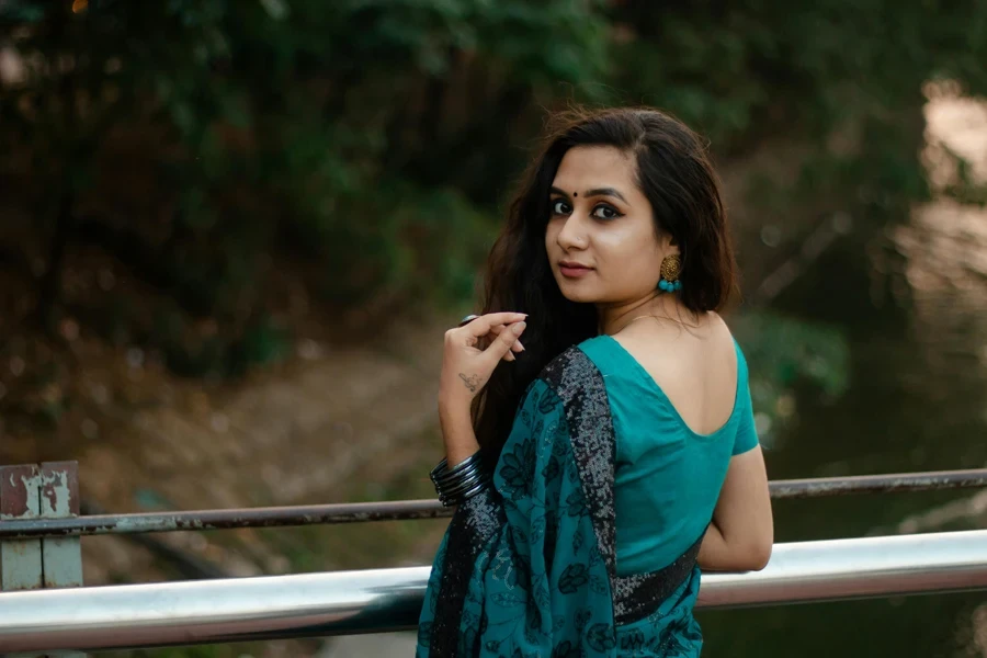 Portrait of a woman in teal sari looking over her shoulder outdoors