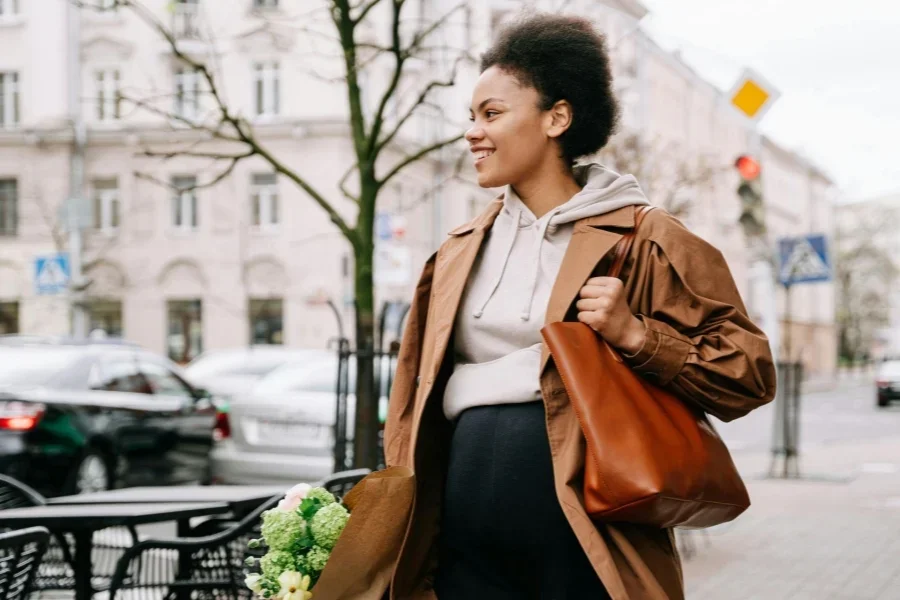 Mujer embarazada con una bolsa marrón sonriendo mientras camina por la calle