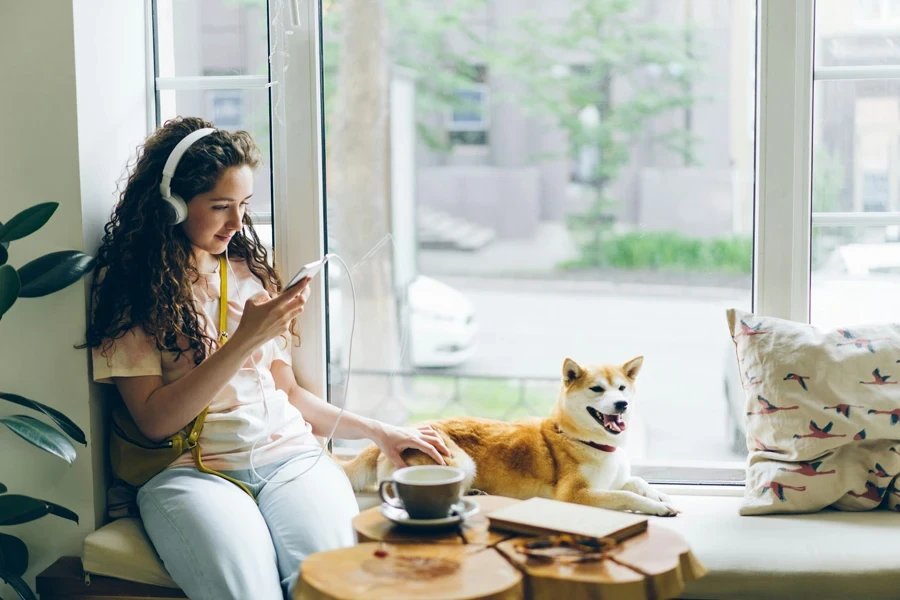 Pretty girl listening to music with headphones using smartphone sitting in cafe