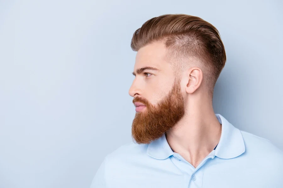 Side profile of man with ginger hair mid drop fade