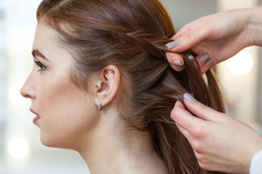 Side profile of woman getting French braids put in