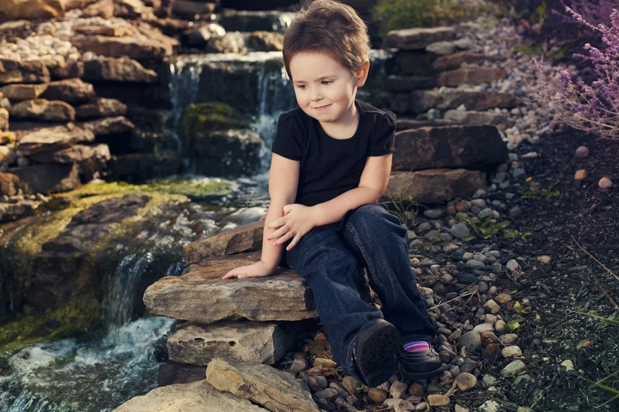 Small child wearing textured pixie cut near waterfall
