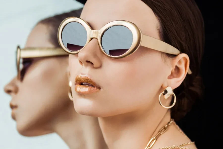 Dama elegante con gafas de sol, varios collares y pendientes de aro.