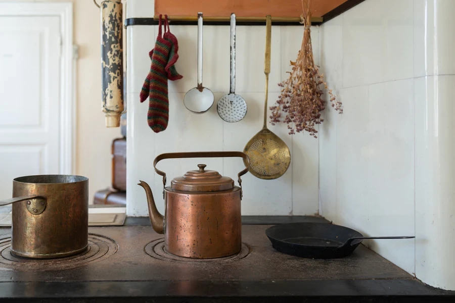 Tall copper kettle sitting on vintage stove top