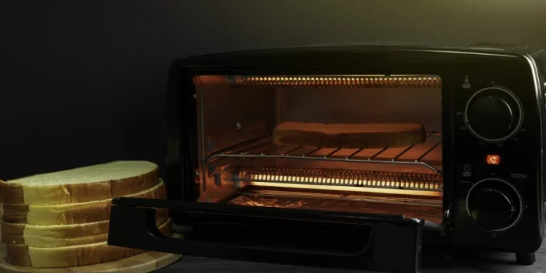 The image displays an electric micro-oven containing bread, likely mid-toast, with a warm glow emanating from within.