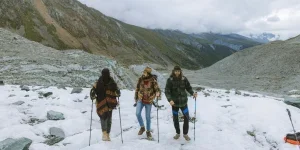Three People Walking on Snow Covered Mountain