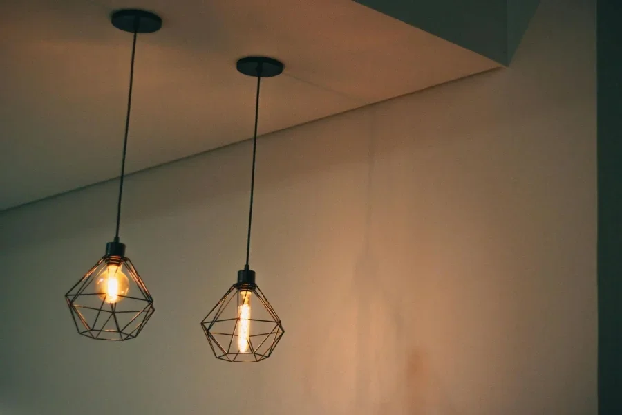 Два черных подвесных светильника на белом бетонном потолке