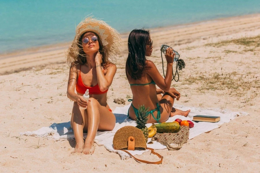 Two Women in Bikini Sitting on Beach Shore