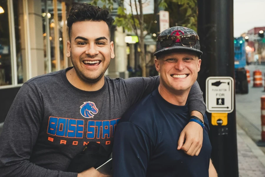 Two men enjoying a sunny day in the city, smiling and embracing joyfully