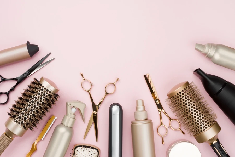 Various hair styling tools on a pink background