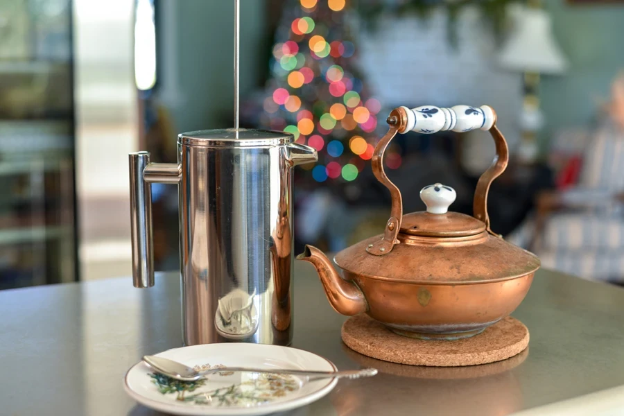 Victorian copper kettle sitting on table next to plate