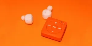 White Earphones Beside Orange Music Player