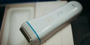 White handheld electric shaver placed on its packaging, showcasing its sleek design and functionality