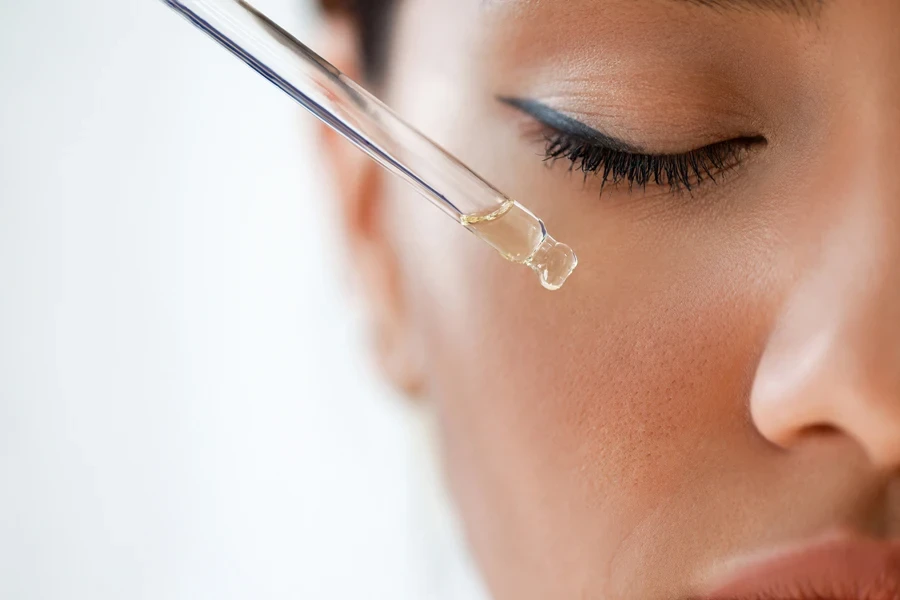 Woman applying face serum with eyes closed