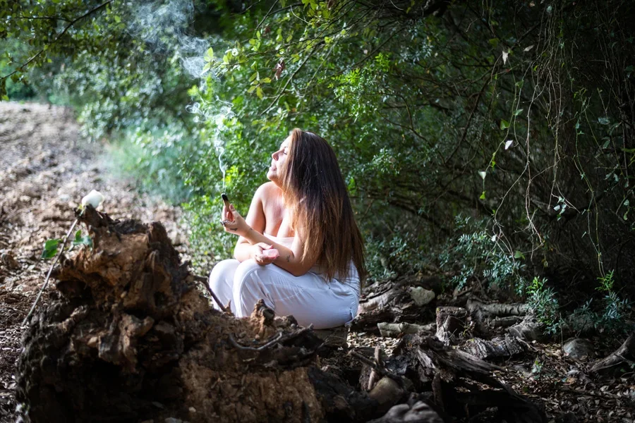 Женщина сжигает пало санто в лесу