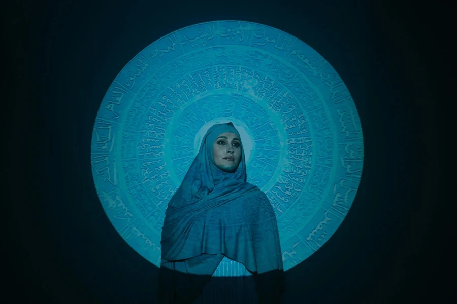 Woman in Blue Hijab Standing Beside Blue and White Wall