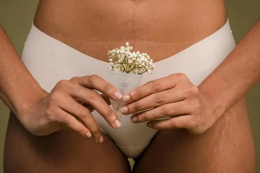 Woman in underwear holding a menstrual cup