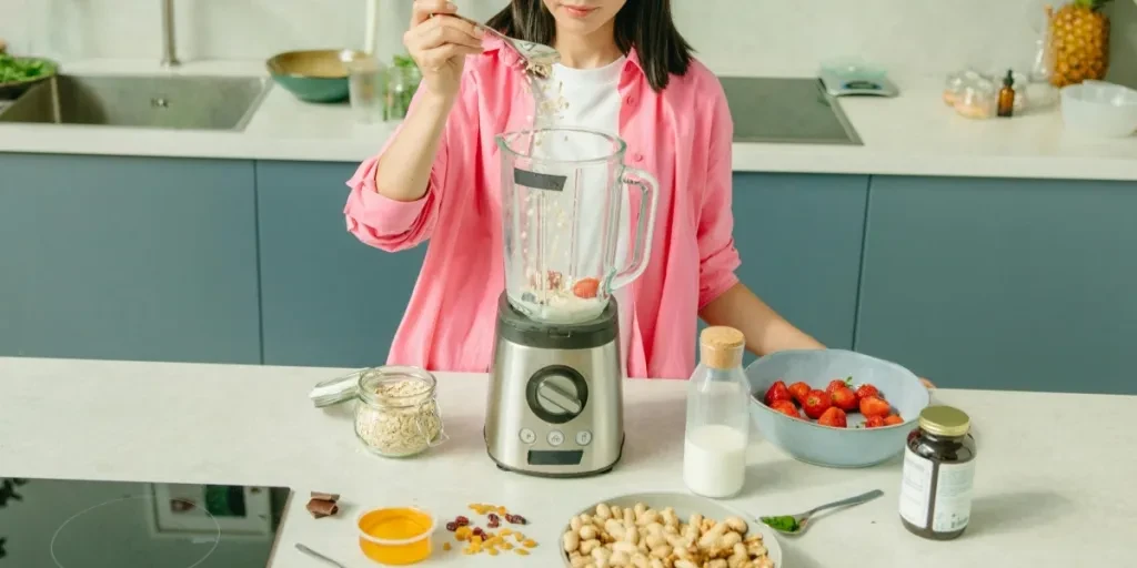 Woman making cashew nut milk with strawberries and cashew nuts