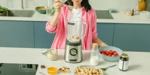 Woman making cashew nut milk with strawberries and cashew nuts