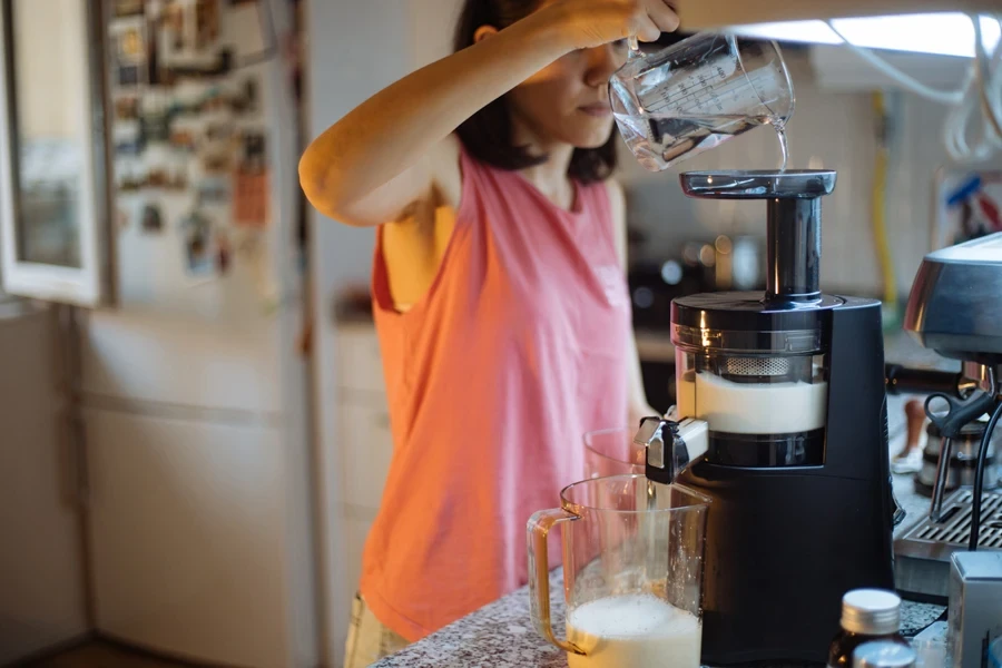 Woman pouring water into a nut milk maker