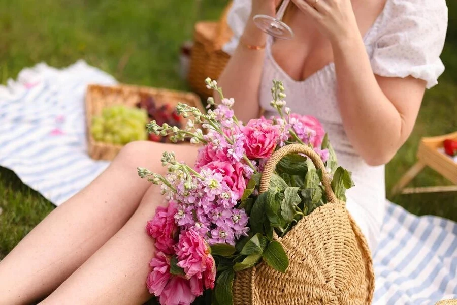 Woman sitting on a blanket with flowers in a basket