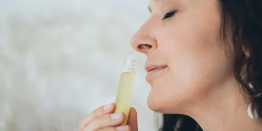 Woman smelling perfume oil with her eyes closed