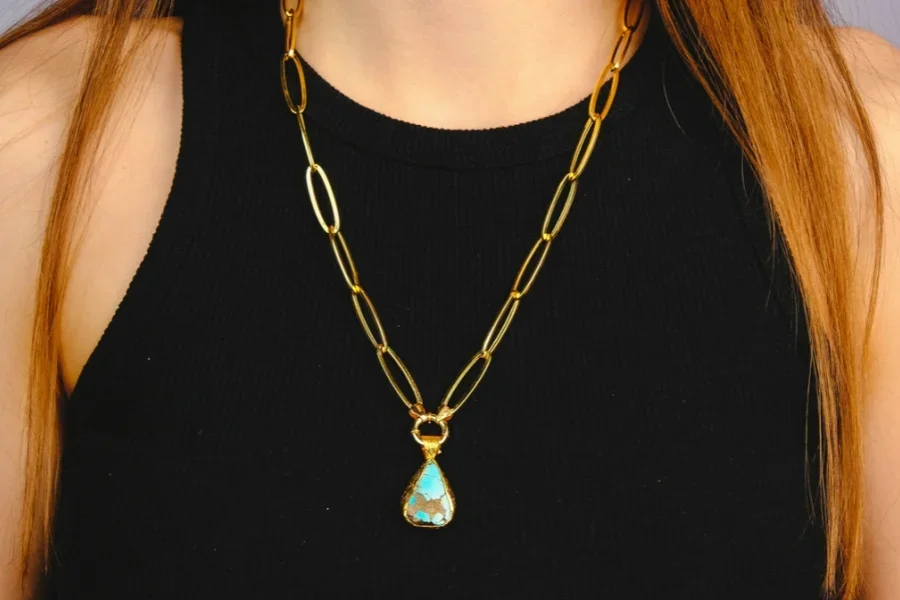 Mujer que lleva un collar de clip de oro con un colgante en forma de lágrima