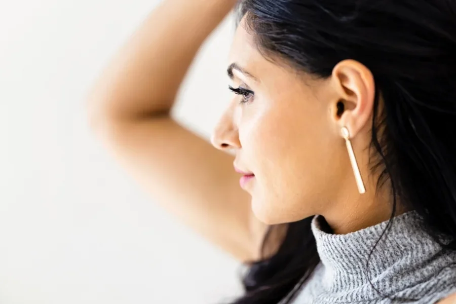 Femme portant des boucles d'oreilles à barre dorée