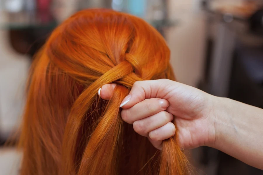 Woman with orange hair at the start of French braid