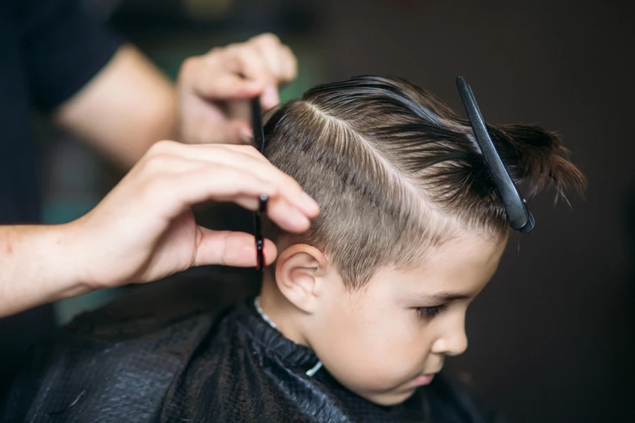 Young boy at hairdressers getting short cut styled