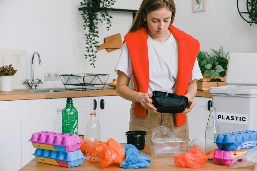 Young woman sorting trash in light kitchen