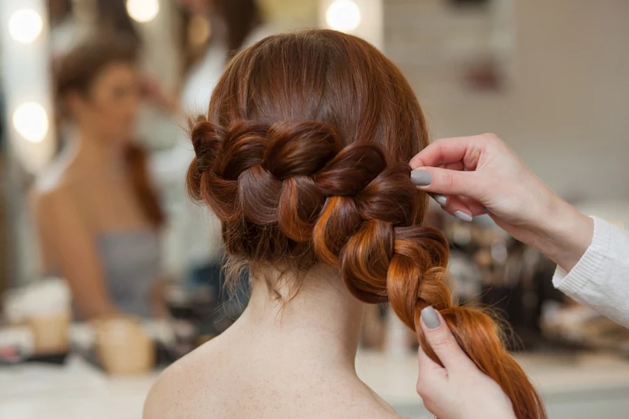 Young woman with ginger hair having French braid done