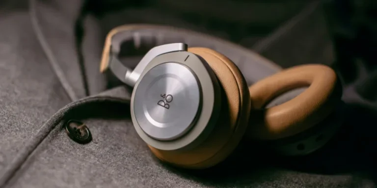 Фотография крупным планом серых проводных наушников на серой тканевой простыне